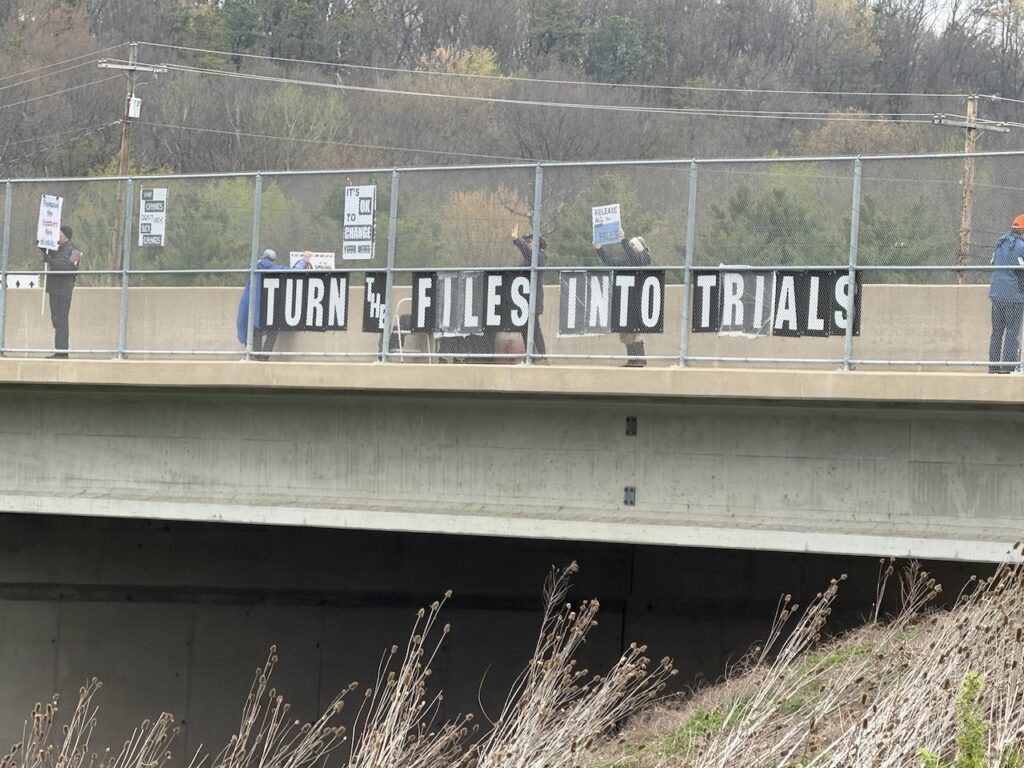 Sign on an overpass reading "Turn the Files into Trials"